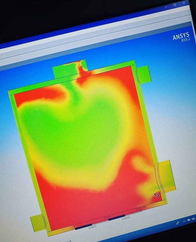 A workshop monitor showing a temperature-contour plot of the furnace cooling study, photographed at an angle.