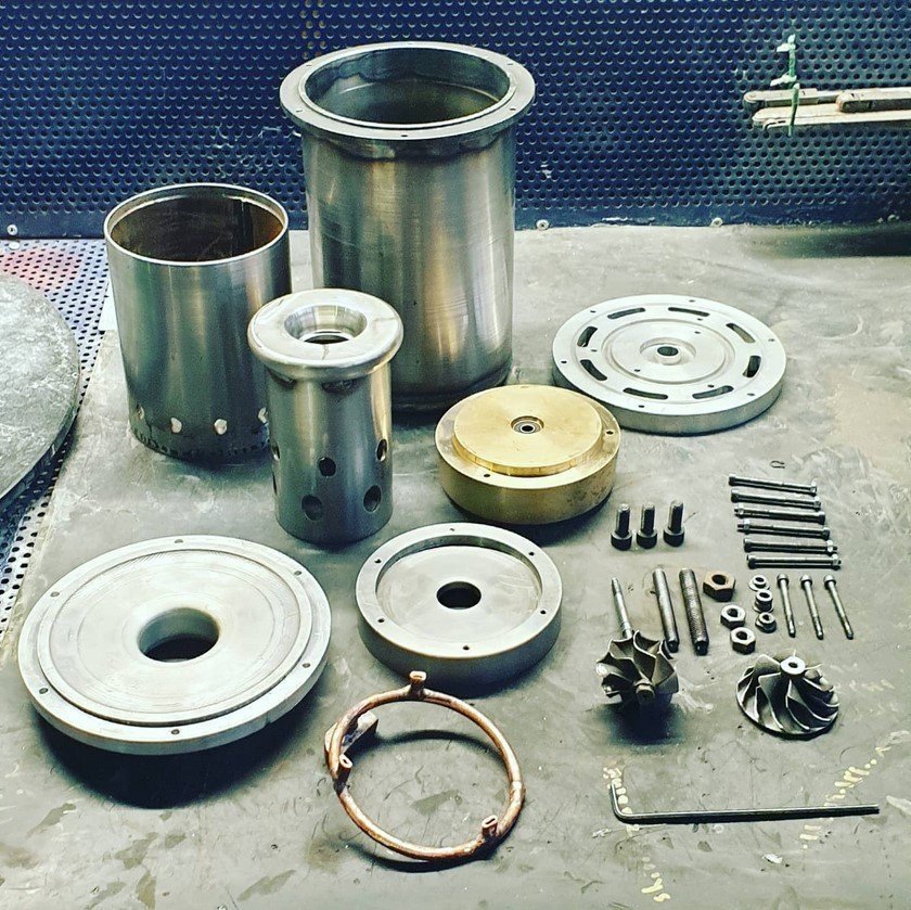 The micro gas turbine during assembly: machined casings, rotor and fastener rings laid out on a workshop bench.